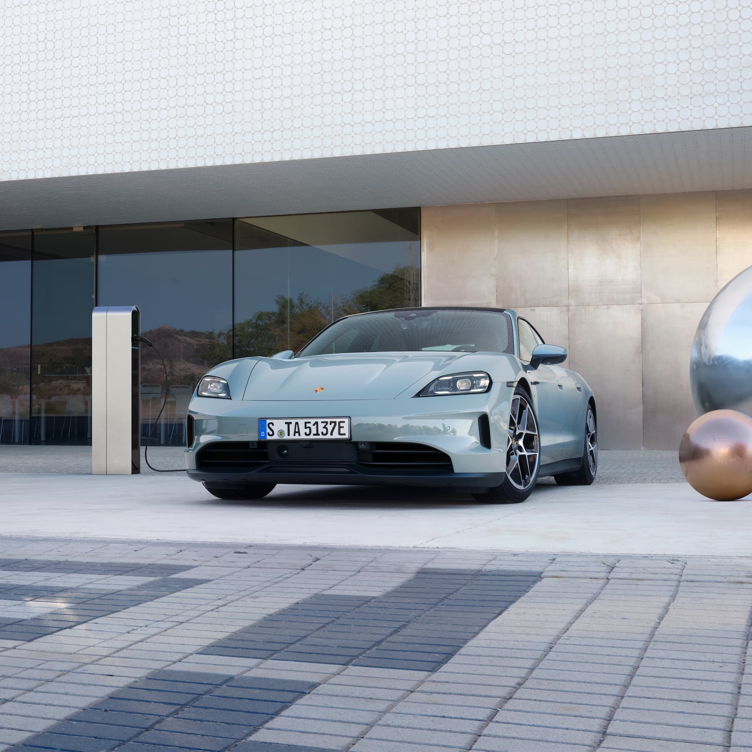 A Porsche Taycan parked outside in front of a modern building.